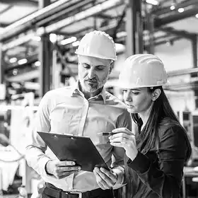 Dos personas; una mujer y un hombre con casco amarillo, aplicando los conocimientos adquiridos de los posgrados para ingenieros.