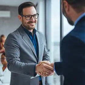 Un par de egresados de Especializaciones en RRHH dan la bienvenida a un auditorio a sus compañeros de trabajo.